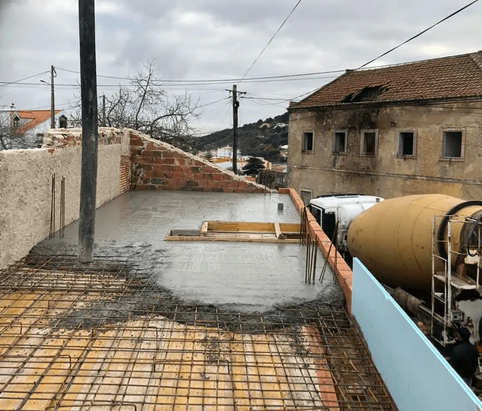 Betonagem de laje térrea com armaduras e autobetoneira em obra