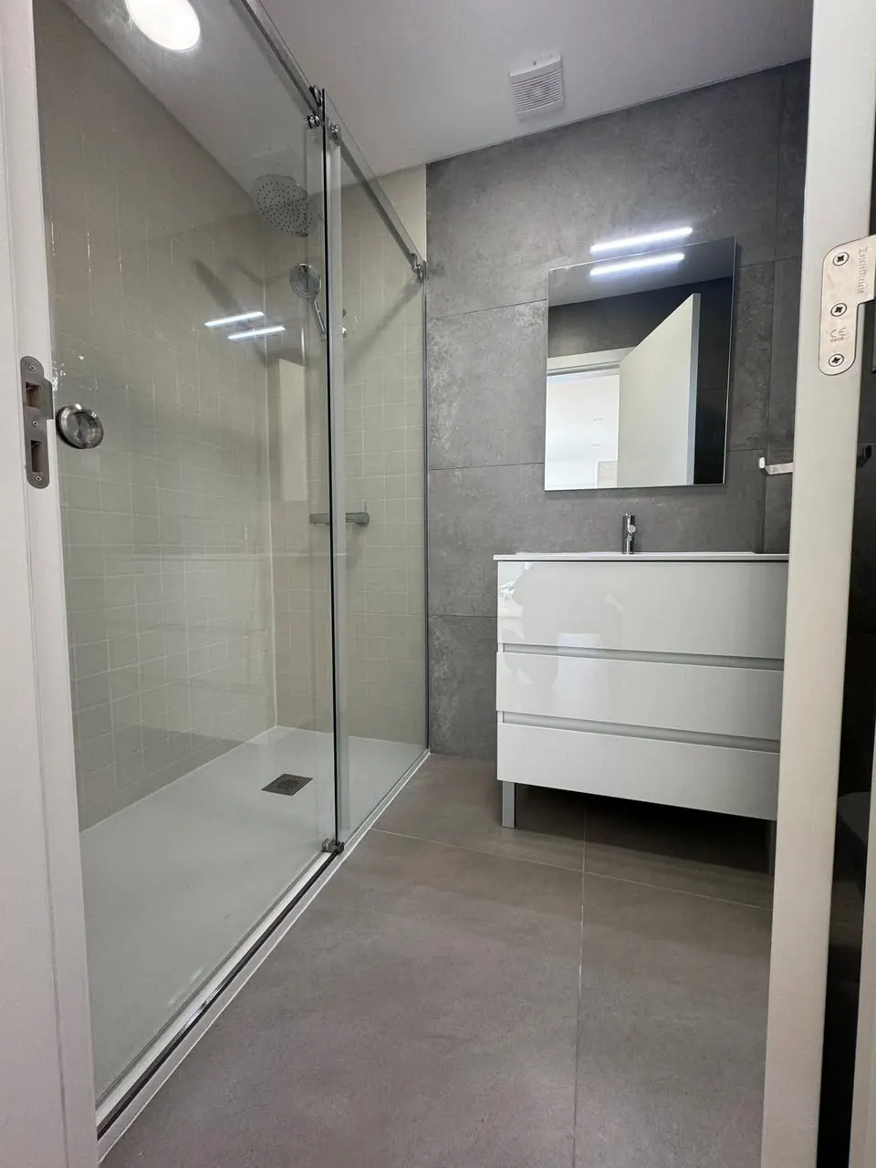 Casa de banho com duche em vidro e revestimento cinza