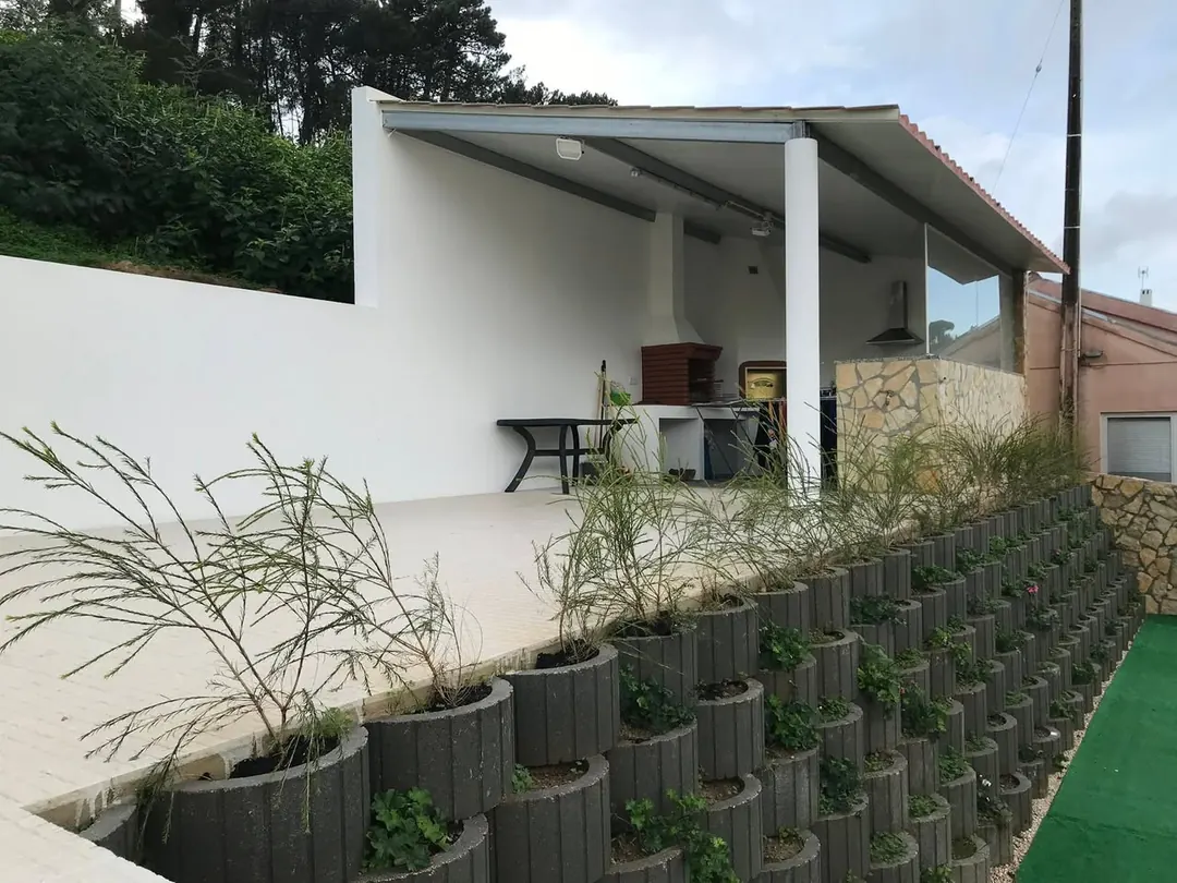 Telheiro com churrasqueira e muro ajardinado em blocos modulares